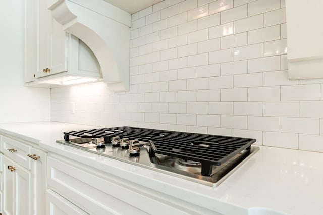 room details with tasteful backsplash, white cabinetry, and stainless steel gas cooktop