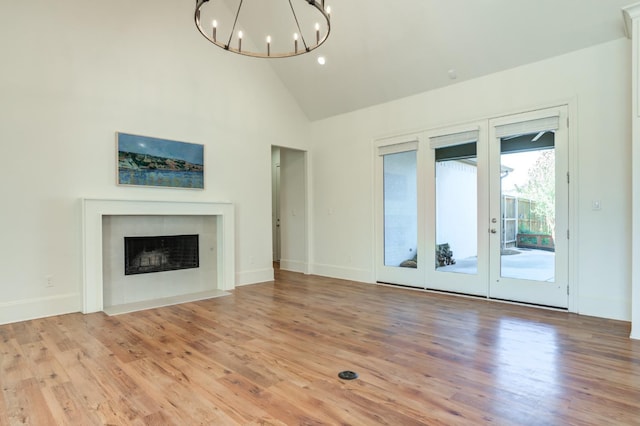 unfurnished living room featuring french doors, high vaulted ceiling, a chandelier, and light hardwood / wood-style flooring