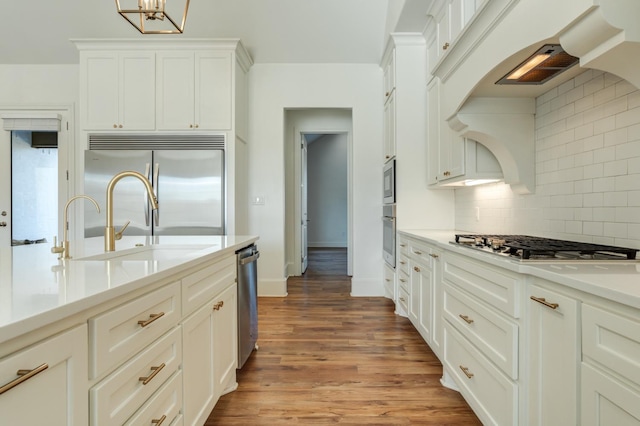 kitchen with appliances with stainless steel finishes, tasteful backsplash, wood-type flooring, sink, and white cabinets