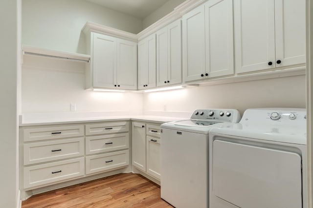 clothes washing area with cabinets, independent washer and dryer, and light hardwood / wood-style flooring