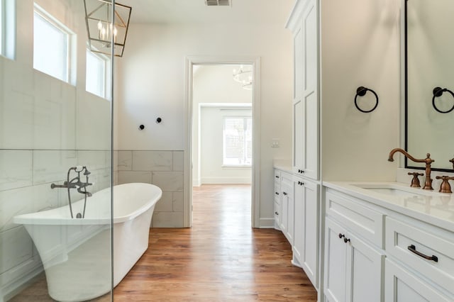 bathroom featuring tile walls, a chandelier, a tub to relax in, hardwood / wood-style flooring, and vanity