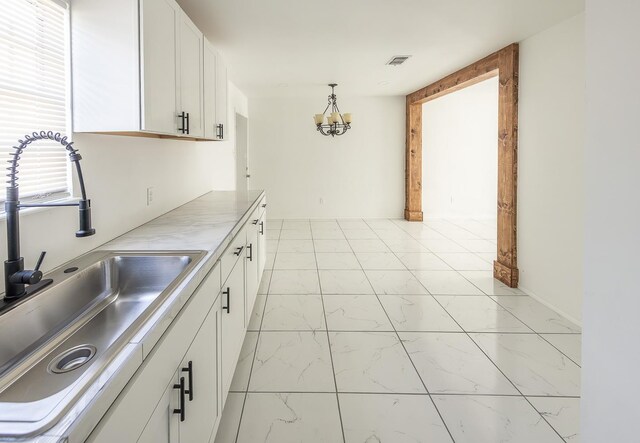 2004 Date Ave, Lubbock, TX 79404 - kitchen with a chandelier, sink, hanging light fixtures, and white cabinets