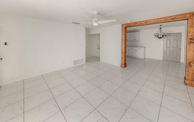 spare room featuring ceiling fan with notable chandelier