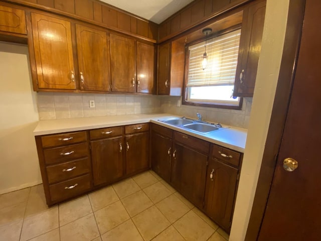 kitchen featuring sink, decorative light fixtures, light tile patterned floors, and backsplash