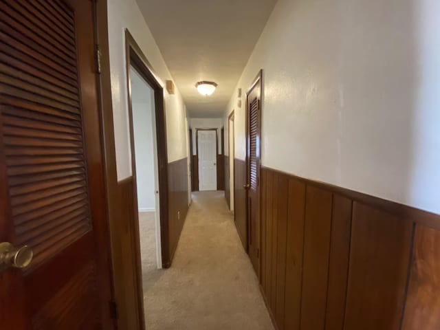 hall with light carpet and wood walls