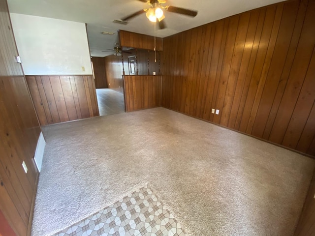 carpeted empty room featuring ceiling fan and wood walls