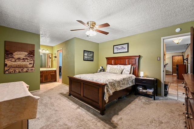 carpeted bedroom featuring ceiling fan, ensuite bath, and a textured ceiling