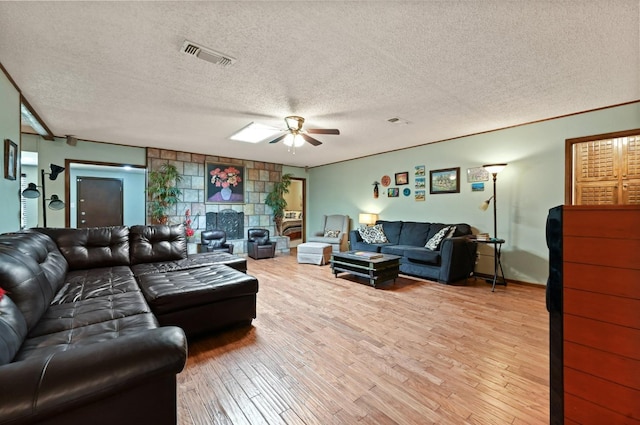 living room featuring ceiling fan, ornamental molding, light hardwood / wood-style floors, and a textured ceiling