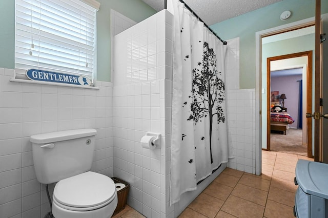 bathroom featuring tile patterned flooring, tile walls, a textured ceiling, a shower with curtain, and toilet