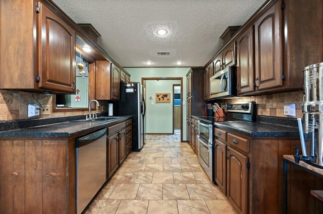 kitchen with sink, backsplash, stainless steel appliances, and a textured ceiling