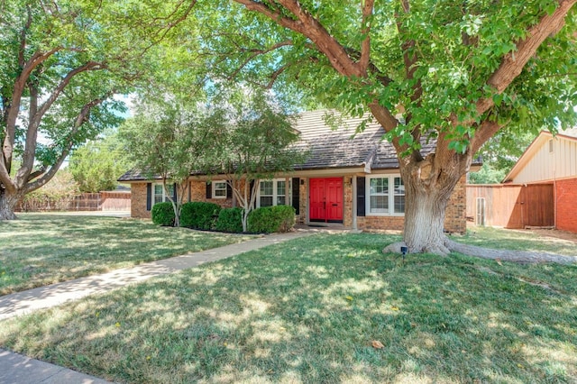 view of front of property featuring fence, a front lawn, and brick siding