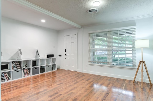 entrance foyer featuring visible vents, baseboards, wood finished floors, crown molding, and a textured ceiling