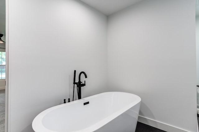 bathroom with a soaking tub and baseboards