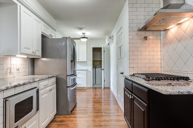 kitchen featuring white cabinets, dark wood finished floors, light stone countertops, stainless steel appliances, and ventilation hood