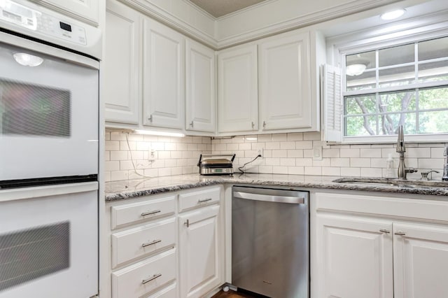 kitchen with light stone counters, white double oven, white cabinets, a sink, and dishwasher