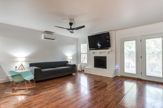 living room featuring ceiling fan, a fireplace, a wall mounted air conditioner, and dark wood finished floors