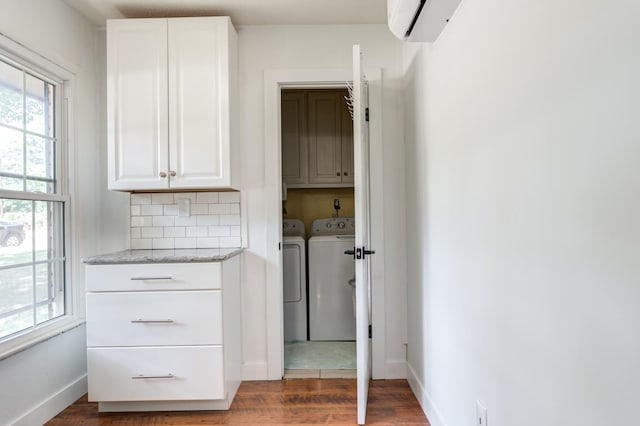 clothes washing area with an AC wall unit, cabinet space, a wealth of natural light, and independent washer and dryer