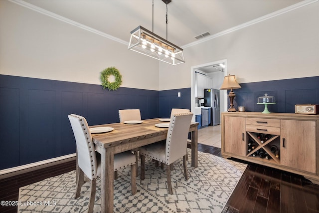 10827 Detroit Ave, Lubbock, TX 79423 - dining room with ornamental molding, wood finished floors, wainscoting, a decorative wall, and a chandelier