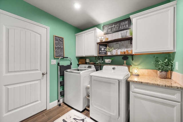 washroom featuring washing machine and dryer, baseboards, cabinet space, and wood finished floors