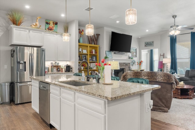 kitchen with stainless steel appliances, visible vents, a sink, a fireplace, and open floor plan