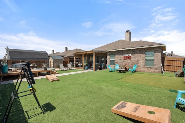 rear view of property with a chimney, fence, an outdoor structure, an outdoor fire pit, and brick siding