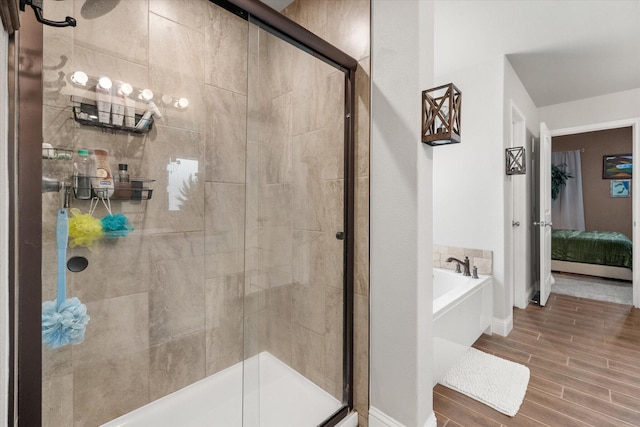 bathroom featuring a garden tub, wood finished floors, ensuite bathroom, and a stall shower