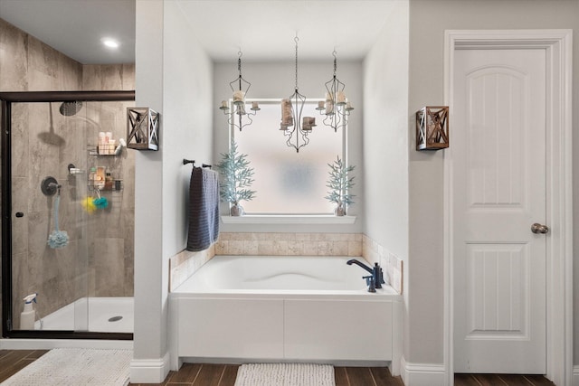 full bath featuring wood finished floors, a garden tub, and a stall shower