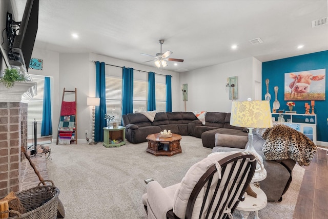 living room featuring a brick fireplace, visible vents, baseboards, and ceiling fan