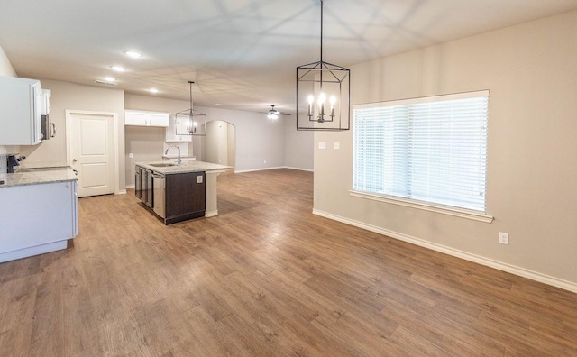 kitchen with pendant lighting, white cabinetry, a kitchen island with sink, and light wood-type flooring