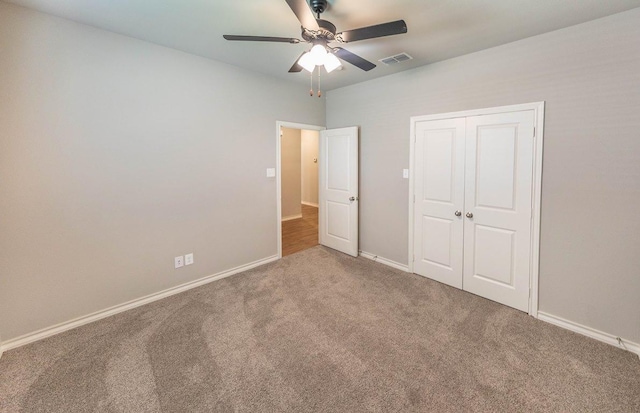 unfurnished bedroom with ceiling fan, carpet flooring, and a closet