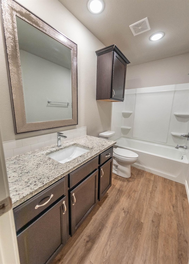 full bathroom with vanity, hardwood / wood-style flooring, shower / bathtub combination, and toilet