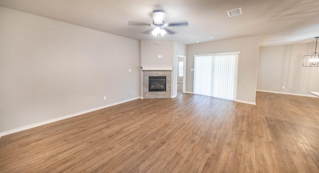 unfurnished living room featuring ceiling fan with notable chandelier and light wood-type flooring