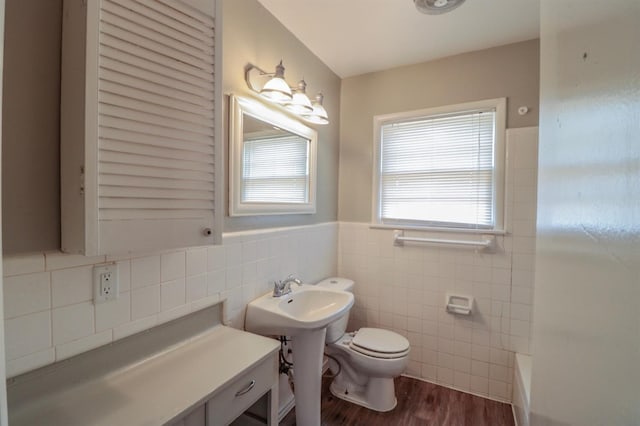 bathroom with hardwood / wood-style flooring, toilet, a bathtub, and tile walls