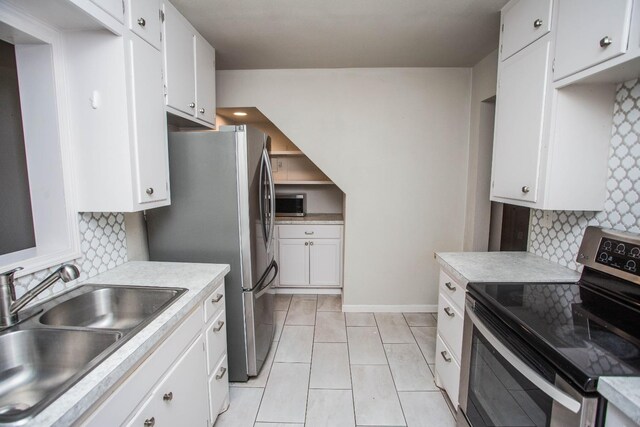 kitchen with sink, white cabinetry, stainless steel appliances, tasteful backsplash, and light tile patterned flooring