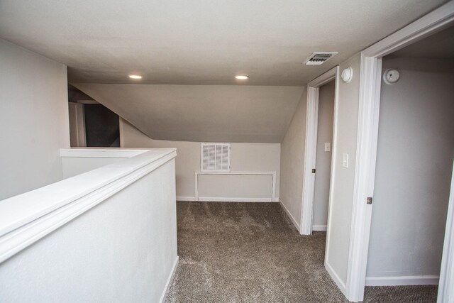 corridor with lofted ceiling and dark colored carpet