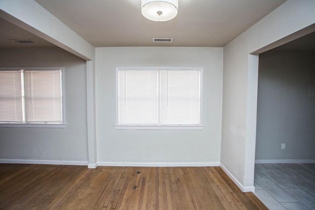 spare room featuring dark hardwood / wood-style flooring and a healthy amount of sunlight