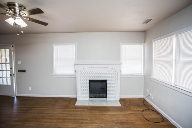 unfurnished living room featuring plenty of natural light, dark hardwood / wood-style flooring, and a tile fireplace