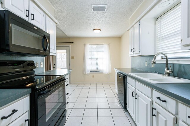 kitchen with light tile patterned floors, visible vents, a sink, black appliances, and white cabinetry