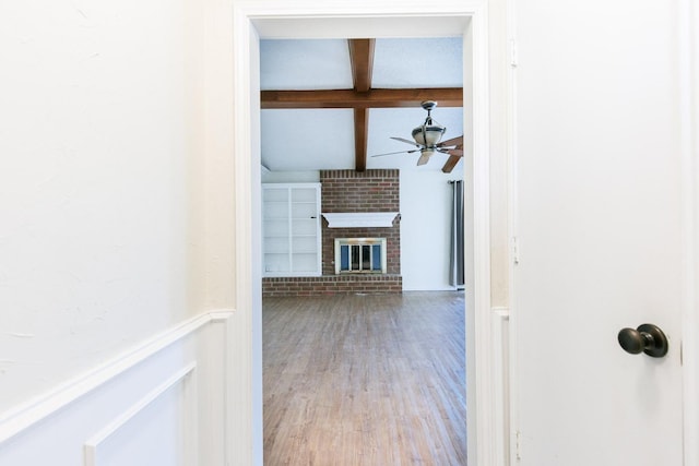 corridor featuring beamed ceiling and wood finished floors