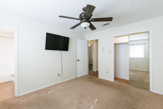 unfurnished bedroom with visible vents, ceiling fan, carpet, a closet, and a textured ceiling