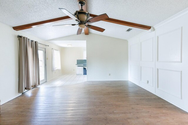 unfurnished living room featuring lofted ceiling with beams, ceiling fan, a textured ceiling, and light hardwood / wood-style floors