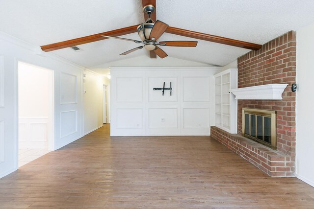 unfurnished living room with ceiling fan, lofted ceiling with beams, a brick fireplace, built in shelves, and light wood-type flooring