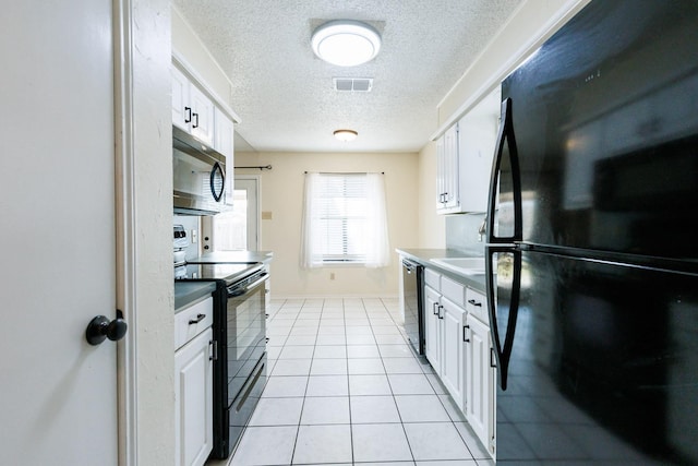 kitchen featuring white cabinets, light tile patterned floors, a textured ceiling, and black appliances