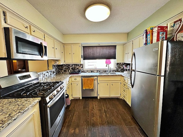 kitchen featuring sink, tasteful backsplash, appliances with stainless steel finishes, dark hardwood / wood-style flooring, and light stone countertops