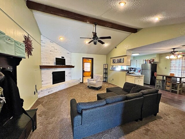 living room featuring lofted ceiling with beams, a brick fireplace, carpet, and a textured ceiling