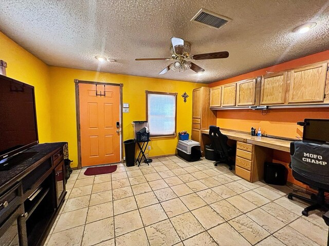 tiled home office with built in desk, a textured ceiling, and ceiling fan