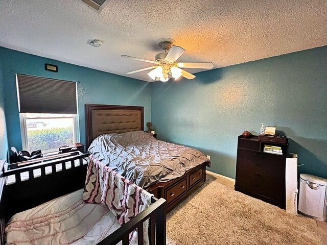 bedroom featuring light carpet, a textured ceiling, and ceiling fan