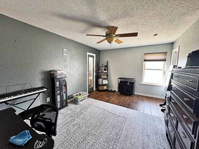 miscellaneous room featuring ceiling fan, dark hardwood / wood-style flooring, and a textured ceiling