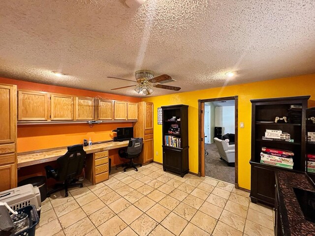 office space featuring ceiling fan, built in desk, and a textured ceiling