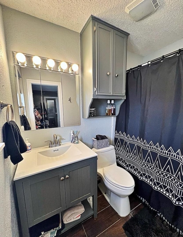 bathroom with vanity, a textured ceiling, and toilet